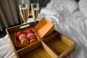 Two champagne glasses and box of assorted macaroons sweets, blurred background