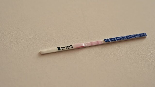 Positive home rapid pregnancy test on a white table. Smoothly appear two stripes. 