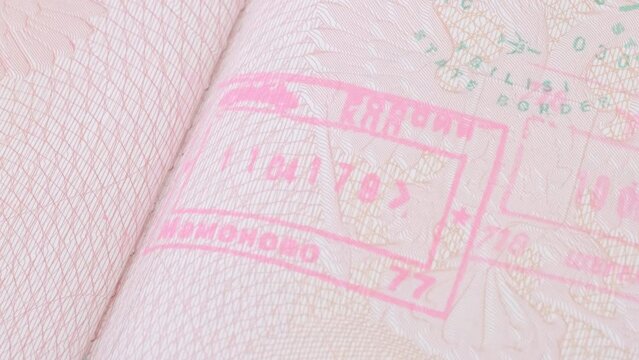 close up part of pages of foreign passport with foreign visas, border stamps, permits to enter countries, concept of traveling around the world, traveler's travel document