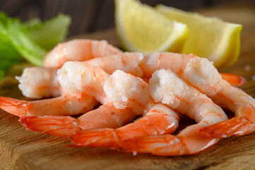 Close-up view of shrimps with lemon and green dill on wooden table