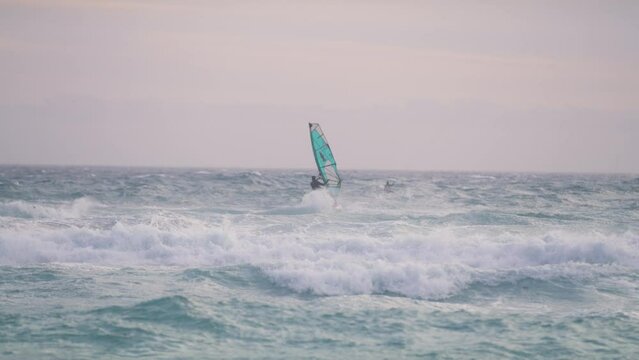 A wind surfer fighting against smaller waves on the ocean