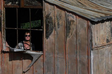Woman looks out old shed.