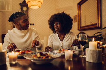 Fototapeta na wymiar Portrait of an african american couple having a romantic dinner date at home and drinking wine