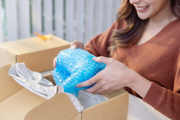 Female Online Sellers Packing a Fragile Vase with Plastic Bubble Wrap Before Sending in the Parcel...