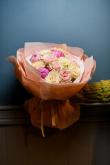 Woman's hand holding luxurious bouquet of yellow, pink roses and pink peonies