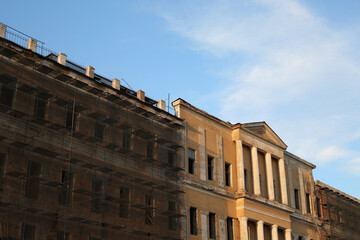 Abandoned building under renovation. An old windowless building with a yellow fa&ccedil;ade and scaffolding for workers. Exterior of an old shabby building
