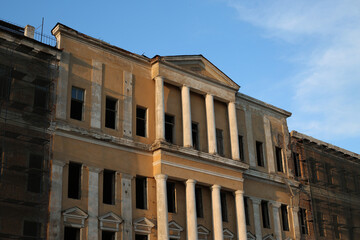 Abandoned building under renovation. An old windowless building with a yellow façade and scaffolding for workers. Exterior of an old shabby building