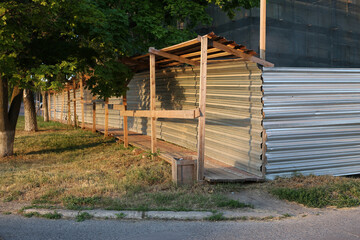 Temporary passage for pedestrians near the construction site. Protective tunnel from construction debris near the fence near the new house under construction. Metal canopy and fence