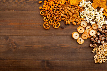 Fast food and salty snacks background. Pretzels nuts and chips top view