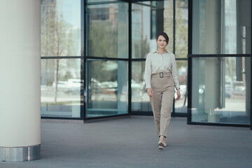 Fototapeta na wymiar Caucasian attractive business woman in a business suit leaves the office building.