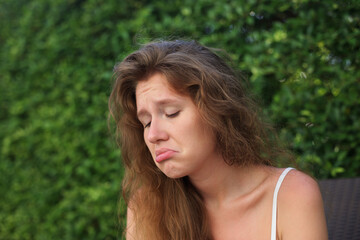 Naklejka premium Portrait of sad upset frustrated young woman on natural green background