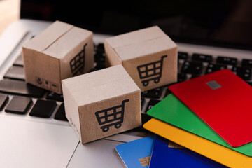 Fototapeta premium Shopping online. Credit card and cardboard box with a shopping cart logo on laptop keyboard. Shopping service on The online web. offers home delivery