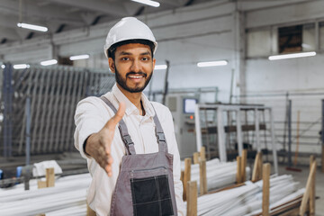 Operator of machine. Industrial worker indoors in factory. Young technician in white hard hat shake hands with someone.