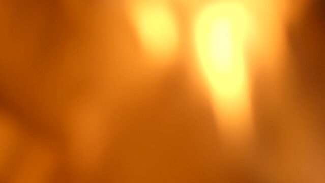 Moving orange and yellow flames. An abstract background with a blurry image of rising flames and twinkling flames.