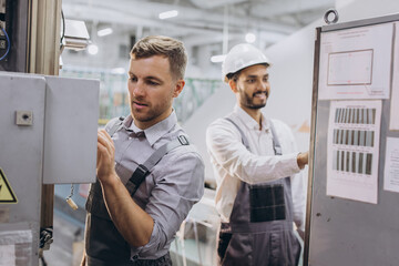 Fototapeta premium Experienced engineers servicing modern industrial manufacturing machine in production factory