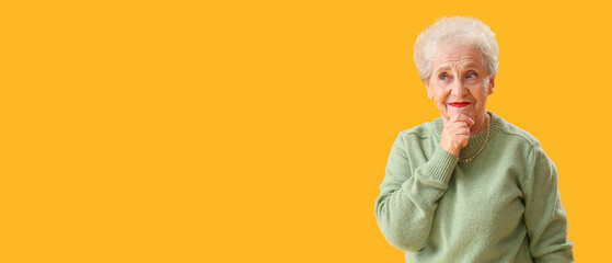 Thoughtful senior woman in green sweater on yellow background with space for text