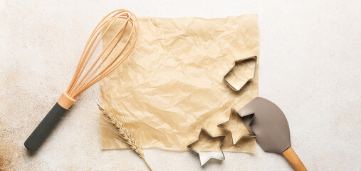 Baking paper and kitchen utensils on light background