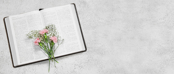 Holy Bible and flowers on light background with space for text