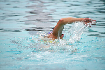 Person swimming laps training racing in an outdoor swimming pool.