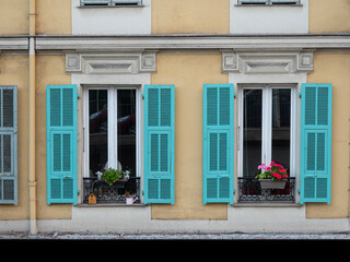 Fototapeta na wymiar Nice in France, colorful facade with shutters and flowers in balcony boxes.