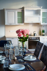 table with dishes and bouquet of roses in the bright kitchen of the living room 