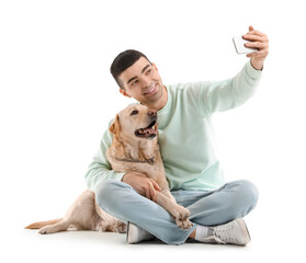 Young man with mobile phone and Labrador dog taking selfie on white background