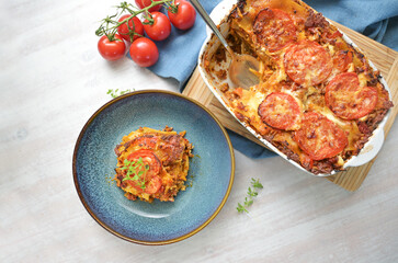 Lasagna, casserole dish of flat pasta sheets, ground beef, vegetables and tomatoes topped with...
