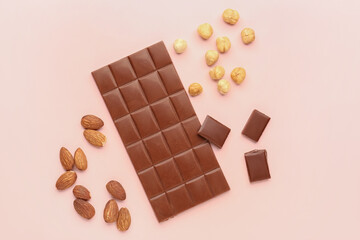 Composition with tasty chocolate and nuts on color background