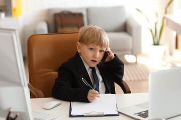 Funny little businessman talking by mobile phone at table in office