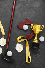 Gold cup with prize medals, golf club and balls on dark background