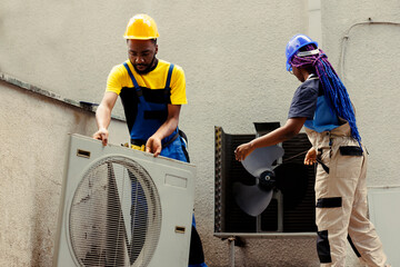 Fototapeta premium African american efficient technicians disassembling hvac system panel with industry techniques and equipment to repair air filters, refrigerant leaks and frozen evaporator coils