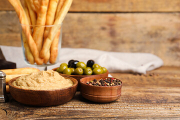 Bowl with tasty hummus on wooden background