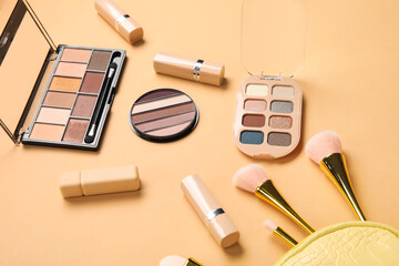Fototapeta na wymiar Cosmetic bag with brushes, eyeshadows and lipsticks on beige background