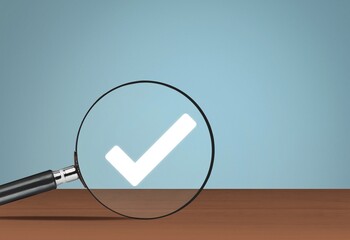 Magnifying glass and white check-mark icon on the desk