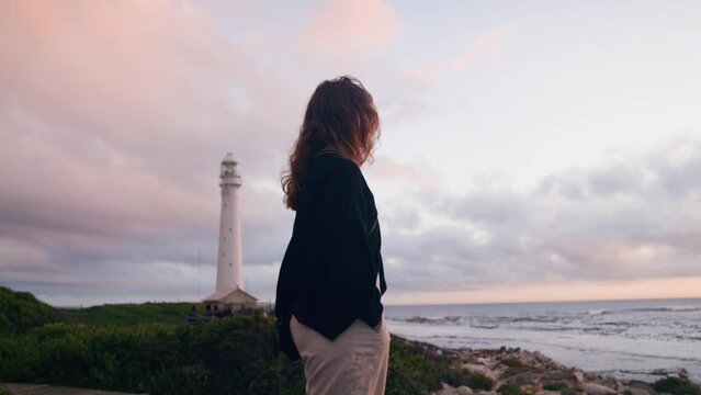 Beautiful young woman looking on the ocean with windy hair infron of lighthouse in Kommetjie  South Africa