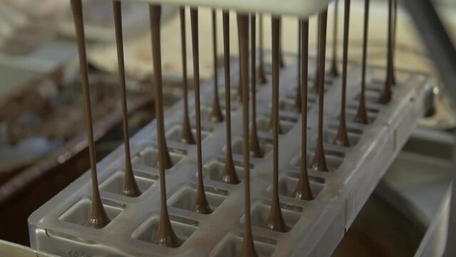 static slow motion close up shot of a pastry chef in a chocolate factory filling a mold with liquid chocolate