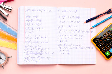 Copybook with maths formulas, calculator and stationery on pink background