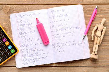 Copybook with maths formulas, calculator, mannequin and pens on wooden background