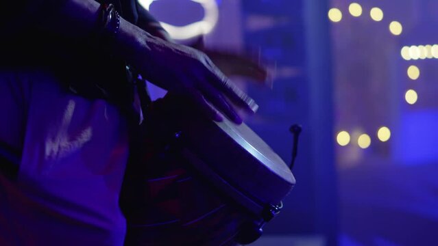 A man bangs his hands on the drums at a party or concert. A video without a face
