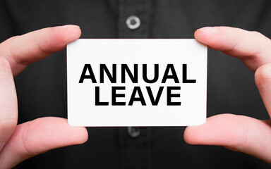 Businessman holding a card with text annual leave, business concept
