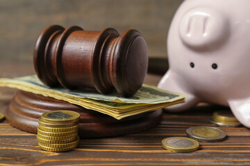 Piggy bank with judge gavel and money on brown wooden background. Concept of bankruptcy