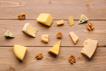 Pieces of tasty cheese with nuts on wooden background