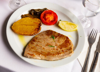 Fried tuna steaks with tomatoes and lemon closeup