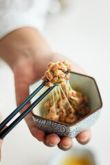 Natto (fermented soybeans) drawing sticky strings on chopsticks,Traditional Japanese food