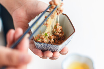 Natto (fermented soybeans) drawing sticky strings on chopsticks,Traditional Japanese food