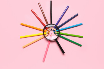 Magnifier with frame made of colorful pencils on pink background