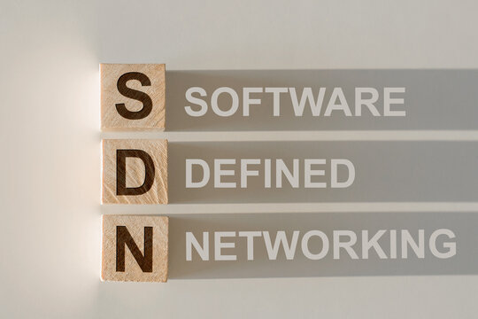 SDN written on wooden cube on gray background