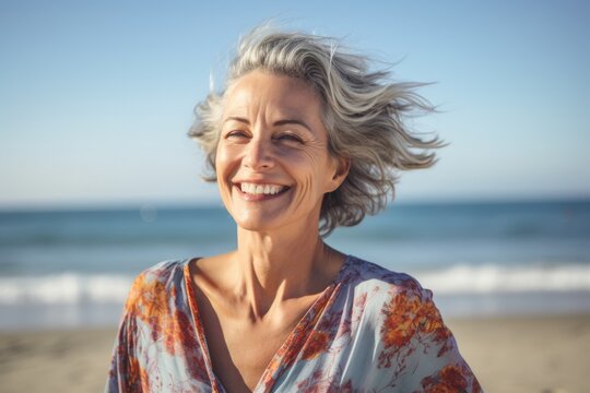 Portrait Of Smiling Senior Woman With Hair Blowing In Wind On Beach