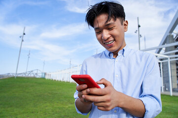 Happy Asian boy using smart phone and smiling with positive attitude. Cheerful Chinese people...