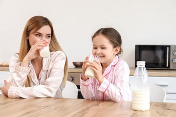 Obraz na płótnie Canvas Little girl with her mother drinking milk in kitchen